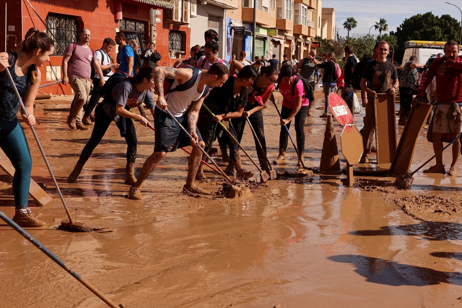 Pessoas varrem lama da rua depois de temporal na Espanha