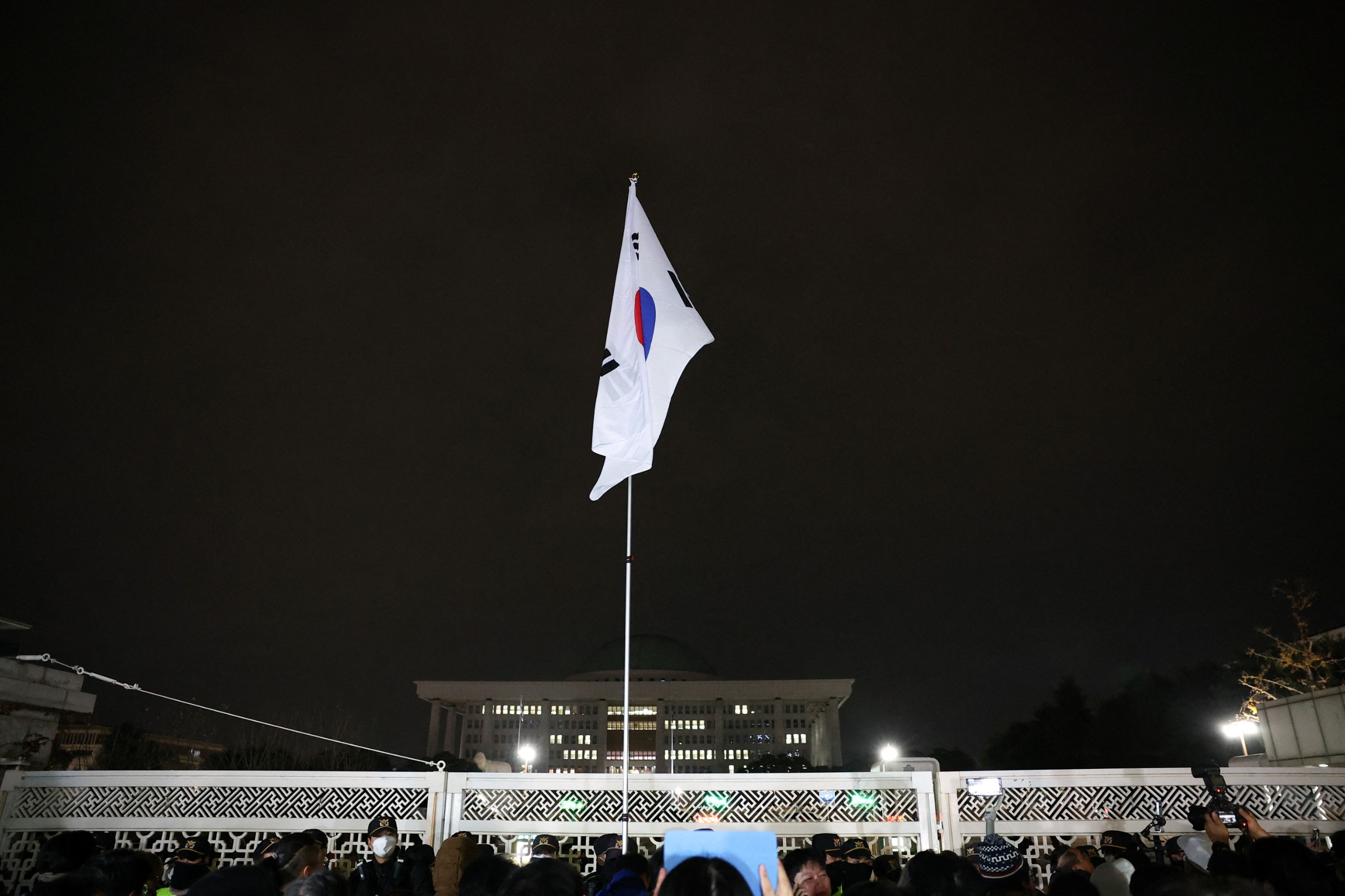 Bandeira da Coreia do Sul ficou pendurada em um mastro do lado de fora do portão da Assembleia Nacional depois do anúncio da Lei Marcial | Foto: Kim Hong-Ji/Reuters