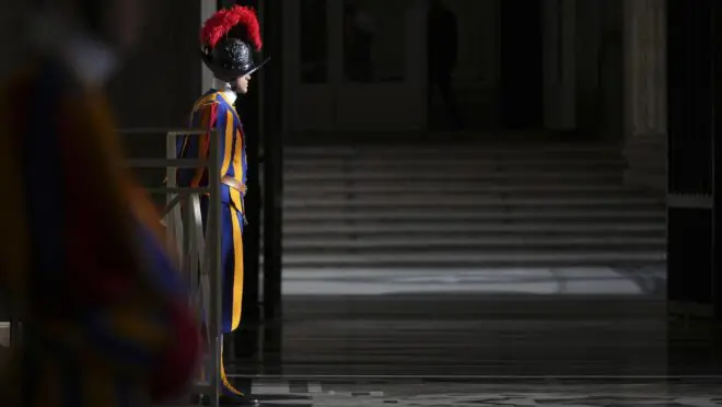origem, uniformes, salários e requisitos Noticias No BR 1 Soldado da Guarda Suíça parado, no Vaticano. Ele usa as vestes tradicionais, azul, amarela e vermelha.